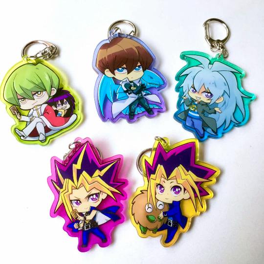Photo of five Yu-Gi-Oh chibi acrylic keychains with metal rings arranged on a white background.