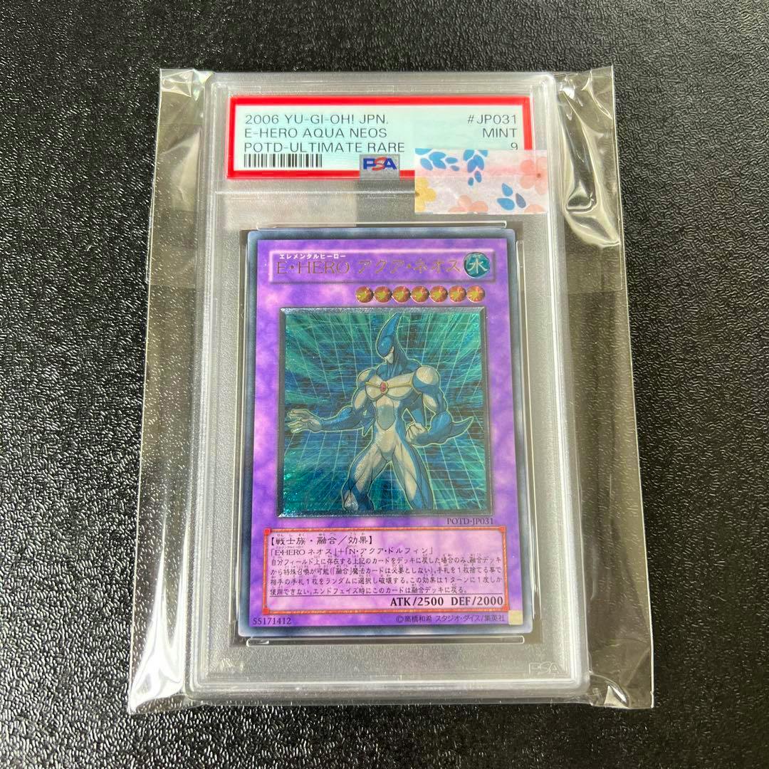 PSA-graded slab containing the Japanese Yu-Gi-Oh trading card 遊戯王 E・HERO アクアネオス graded PSA 9, shown in a clear sleeve on a black textured surface.