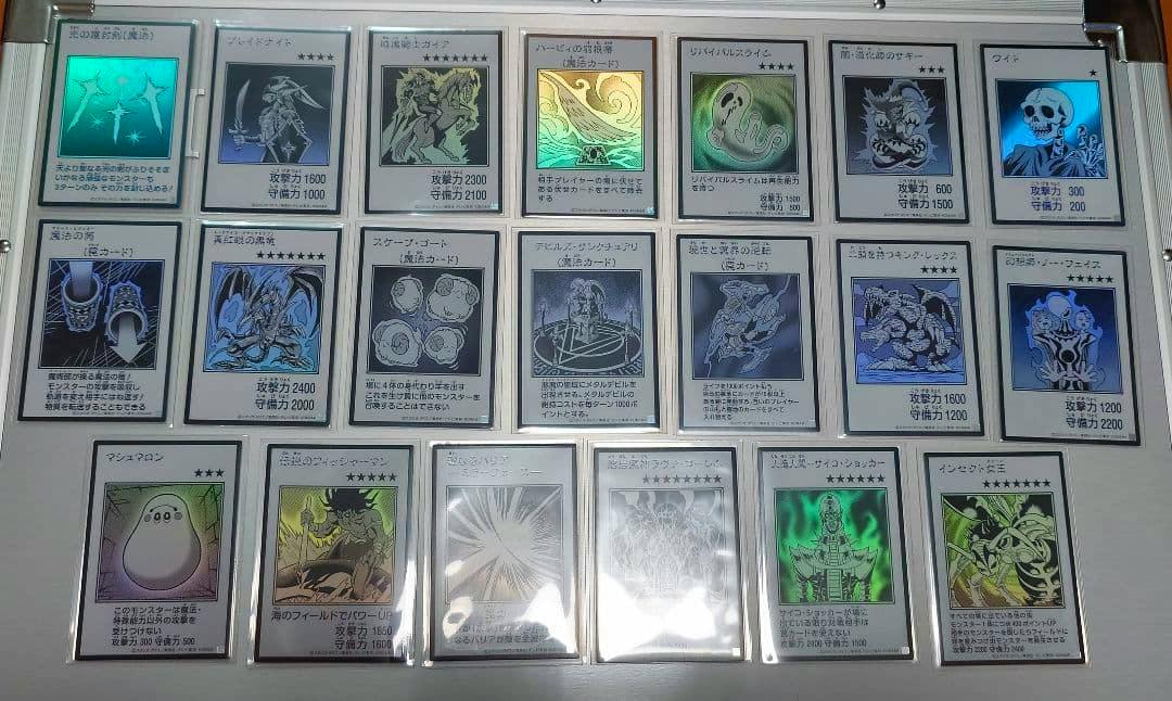 Several manga-style monochrome Yu-Gi-Oh trading cards in protective sleeves arranged in rows on a flat white surface.