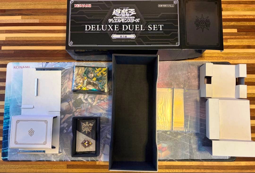 An opened 閃刀姫 デラックスデュエルセット 遊戯王 box and its included card accessories laid out on a playmat.