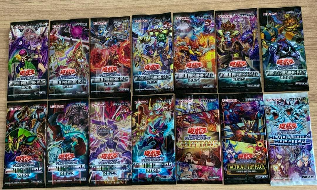 Photo of 14 sealed Yu-Gi-Oh trading card booster packs arranged on a wooden surface.