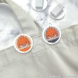 Photo of two round acrylic hair clips showing an orange‑haired character face clipped to fabric.