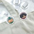 Photo of two round acrylic hair clips with character-face designs placed on light-colored fabric.