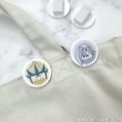 Photo of two round acrylic hair clips from the set showing character face designs on a light fabric background.