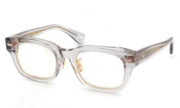 Three-quarter view of the YUICHI TOYAMA:5 glasses frame in translucent gray acetate with visible gold-tone inner rim and nose pads.
