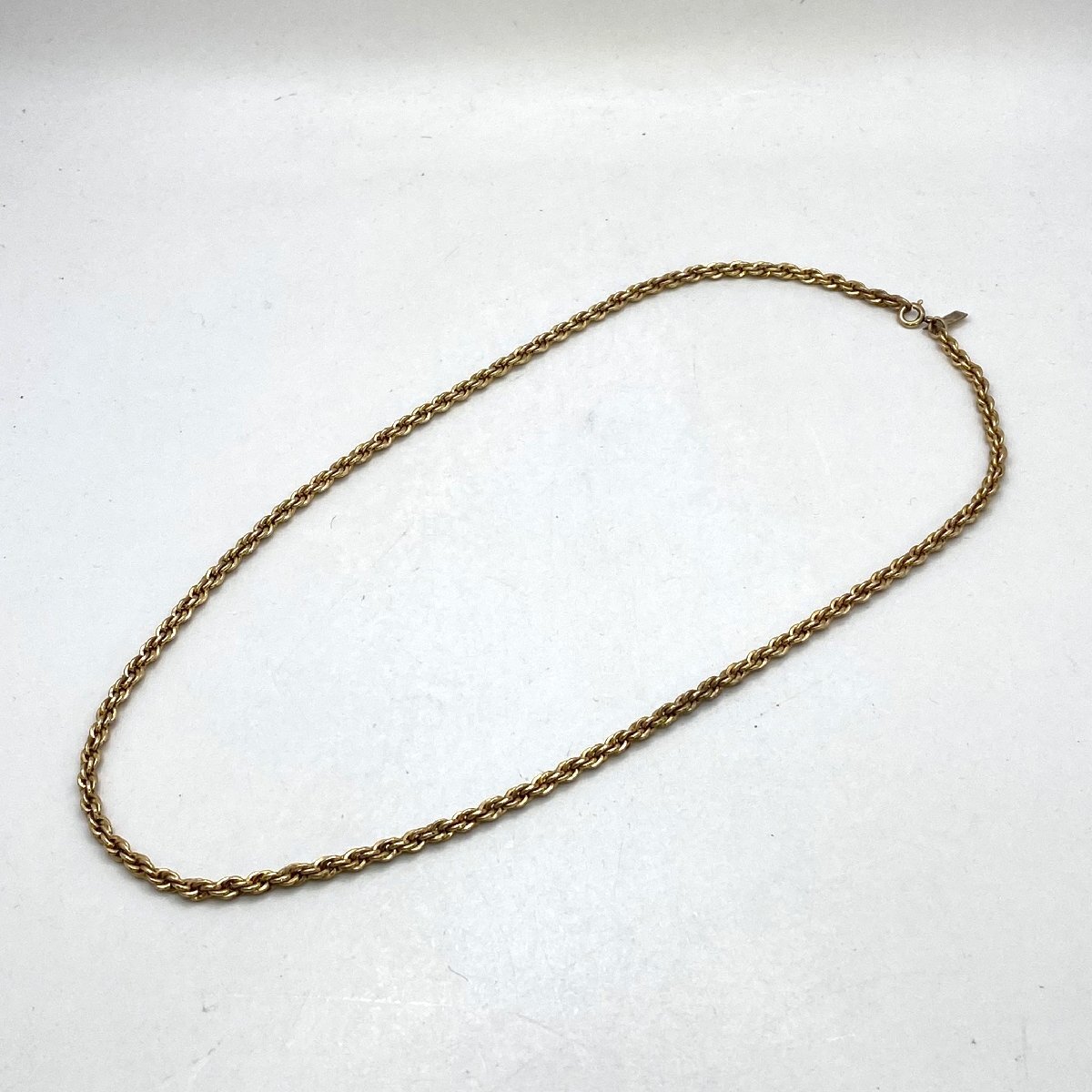 Yves Saint Laurent gold-color chain necklace laid flat on a white background.