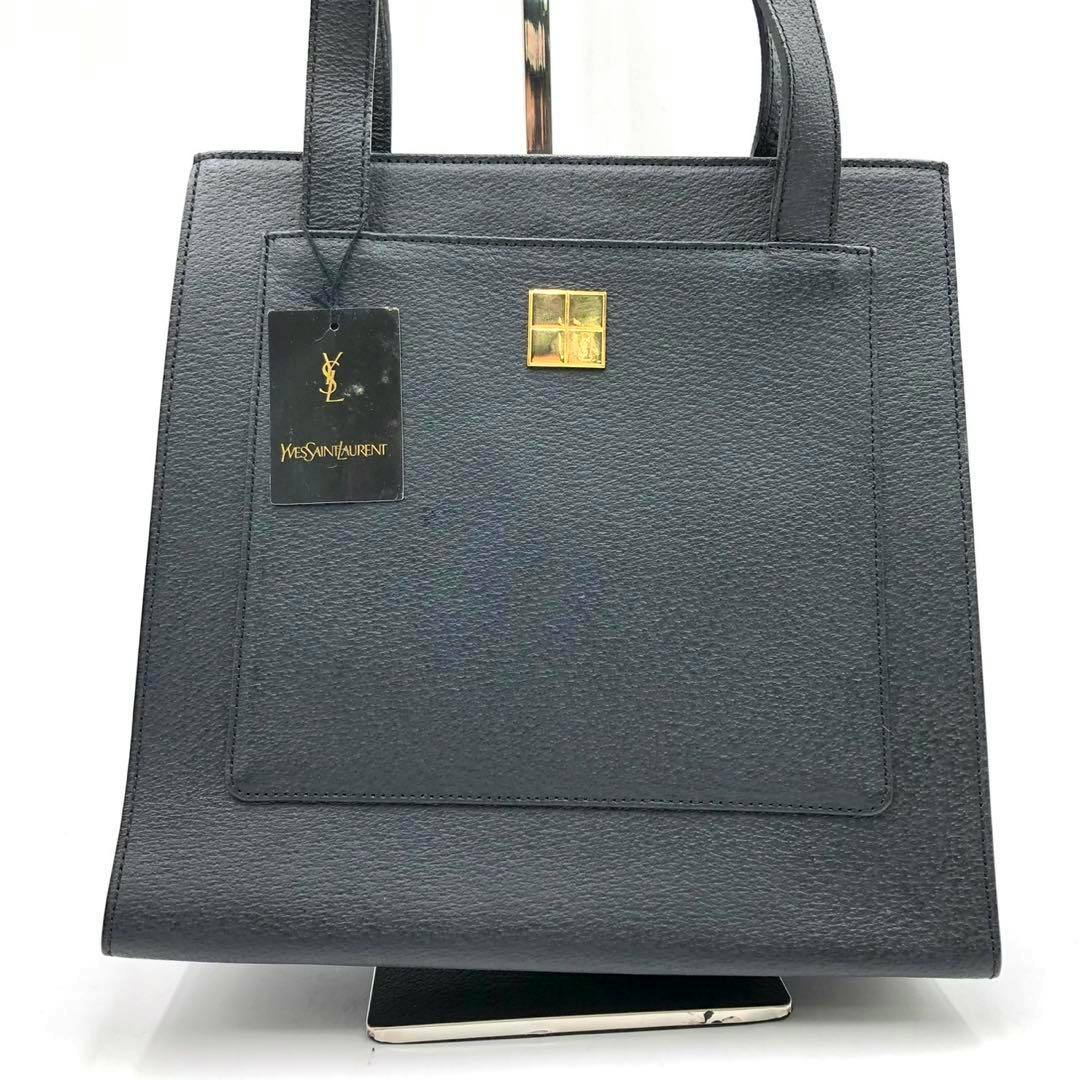 Front view of the black Yves Saint Laurent cow leather tote bag showing gold square hardware and a hanging YSL tag.