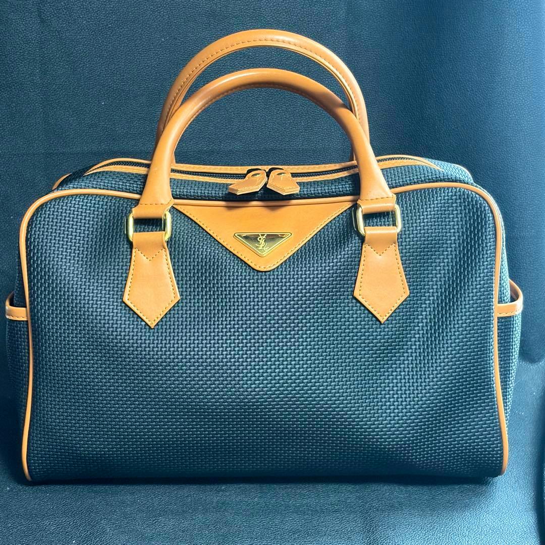 Front view of a mini canvas Boston handbag with tan leather trim and a triangular YSL logo plate.