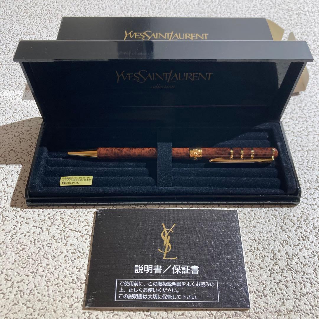 Yves Saint Laurent ballpoint pen displayed in an open presentation box with foam insert and an accompanying booklet.