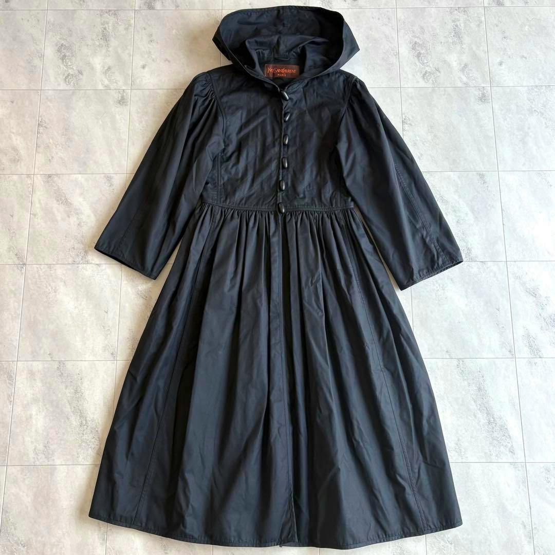 Black long hooded women's cotton coat laid flat, showing A-line gathered skirt and front button closure.