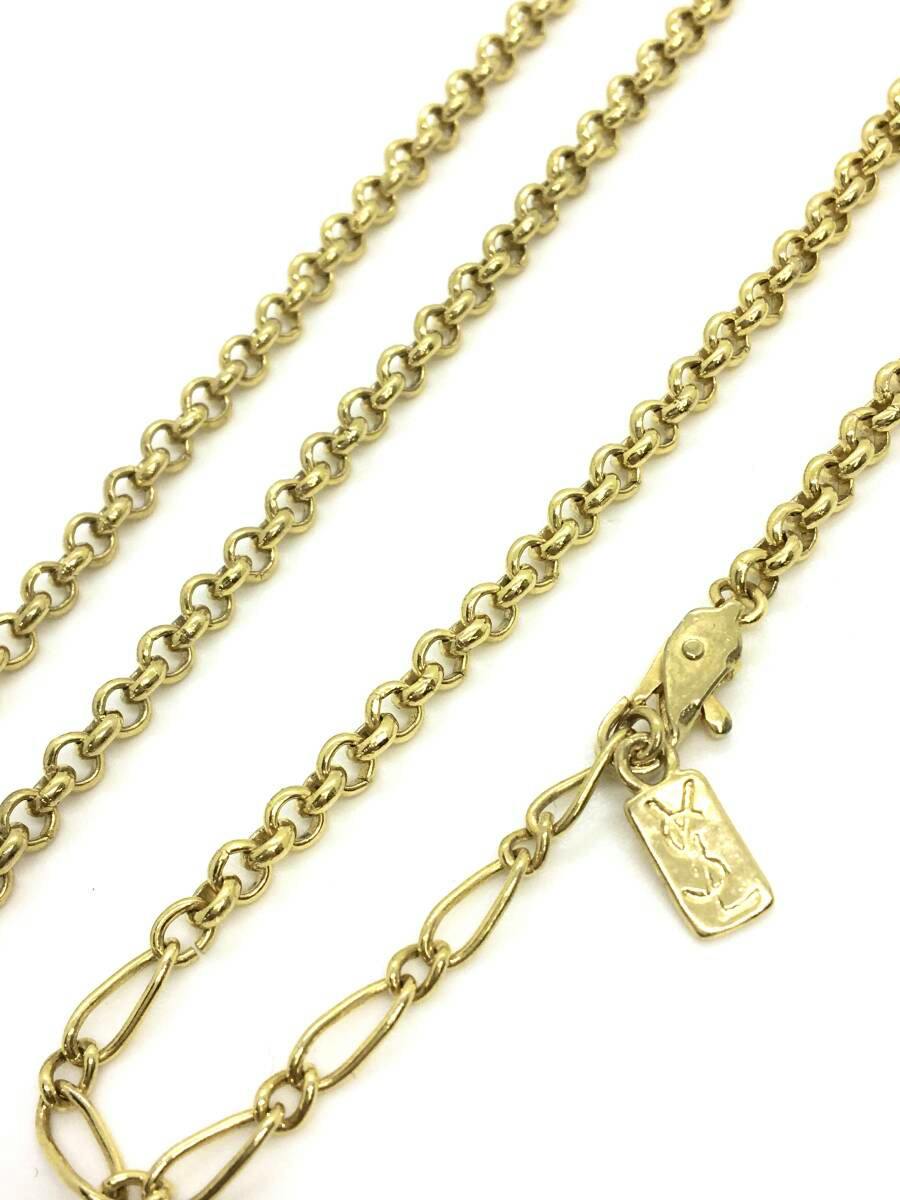 Gold-colored chain necklace laid flat on a white background showing the chain links, lobster clasp, and a small rectangular YSL logo tag.
