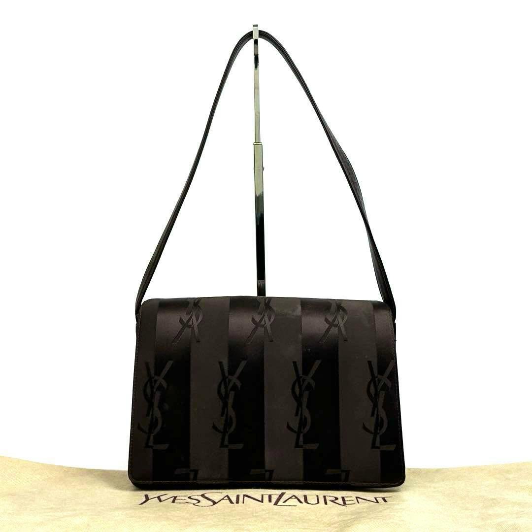 Front view of a YSL patterned nylon and leather one-shoulder bag hanging from a stand on a Yves Saint Laurent dust bag.