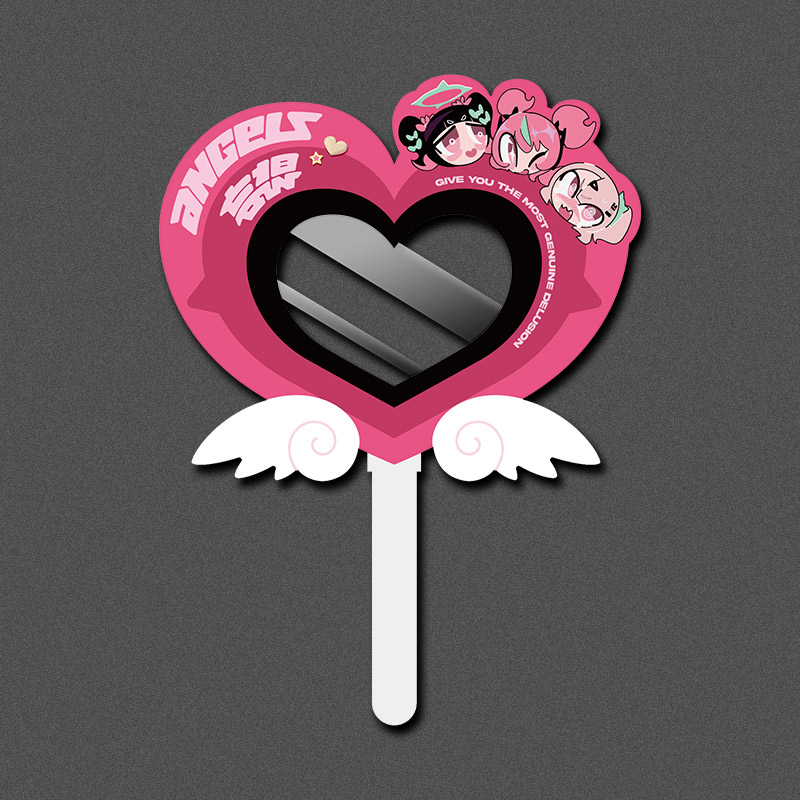Pink heart-shaped paper fan with a heart-shaped cutout center, white handle and wing decorations, and three small illustrated character faces on the upper right.