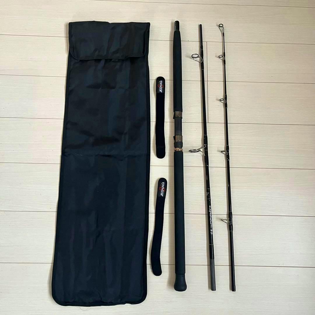 Disassembled fishing rod (three sections) with foam handle, two protective straps, and a black carrying bag laid out on a light wood floor.