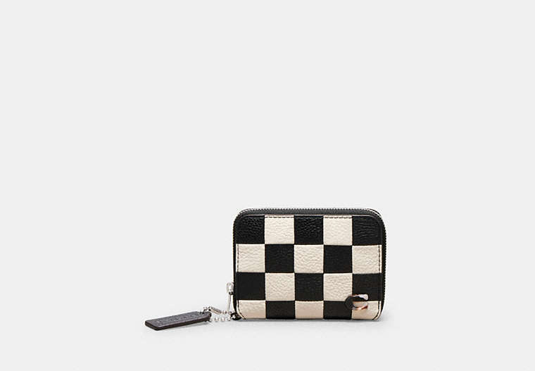 Front view of a checkerboard-pattern zip-around cow leather wallet with a zipper pull and tag.