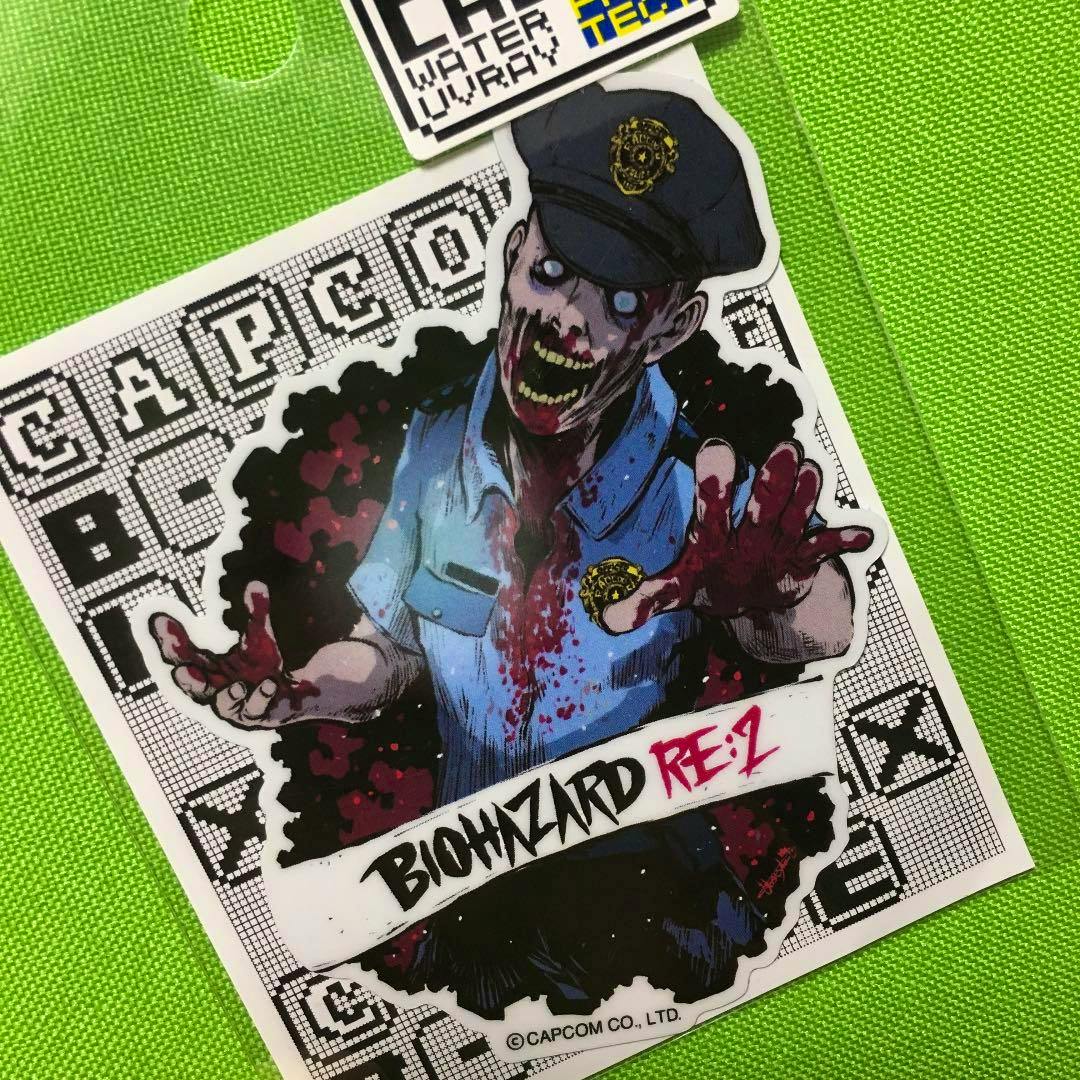 Paper sticker showing a bloodied zombie police officer illustration with the text "BIOHAZARD RE:2" on a green background.