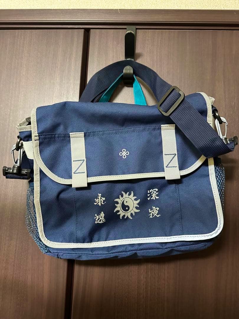 Front view of a navy nylon 3Way bag with a flap, printed design on the front, and an adjustable shoulder strap.