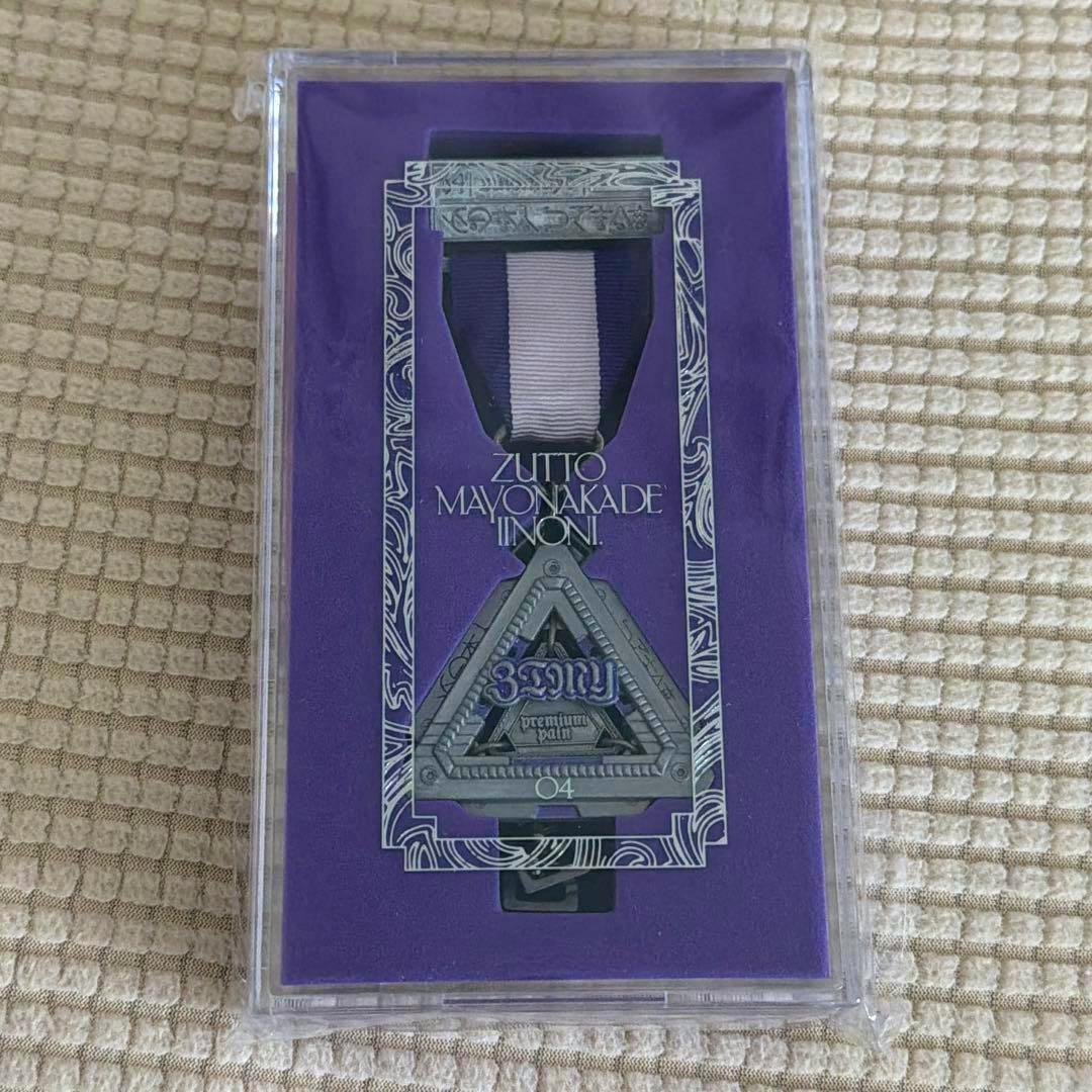 A ZUTOMAYO PREMIUM member-only triangular medal badge with ribbon displayed in a clear plastic case on a purple backing.